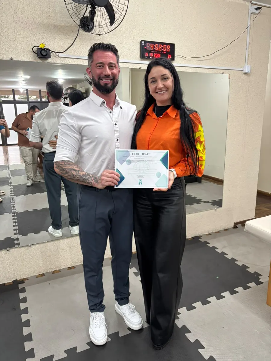 Aluna com certificado ao lado do professor