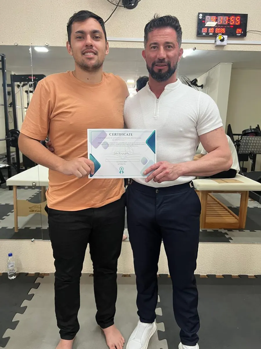 Aluno com certificado ao lado do professor